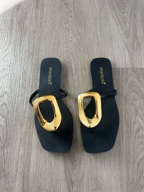 Shoe Dazzle Black Thong Sandals with Shiny Gold Ornament
